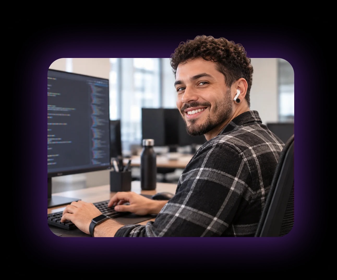 Desenvolvedor de software sorrindo diante de um monitor com código